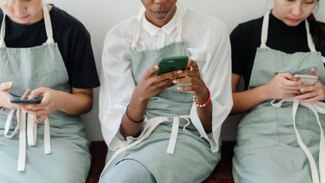 crop focused multiethnic baristas using smartphones